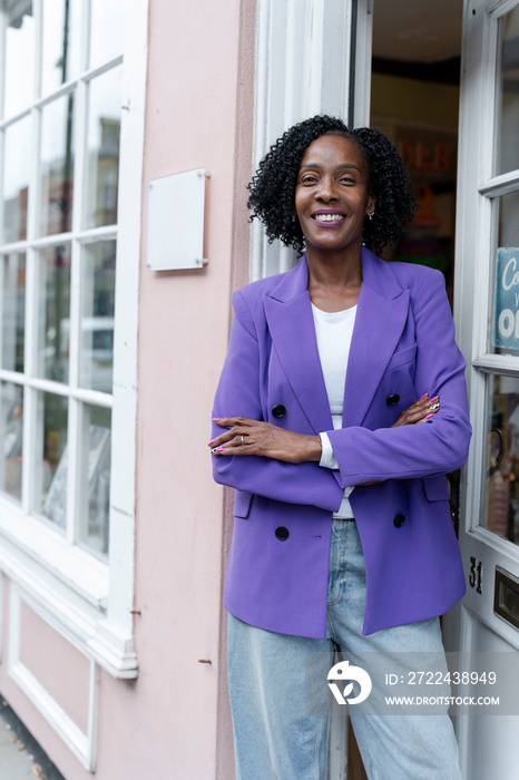 Portrait of female business owner standing in front of open store