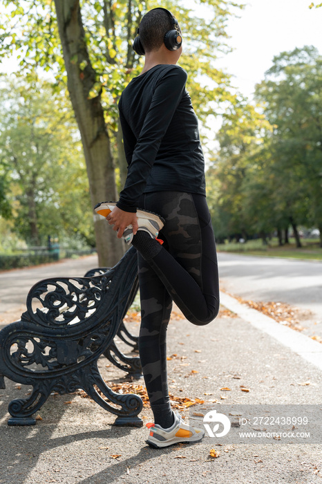 Woman stretching leg at bench in park