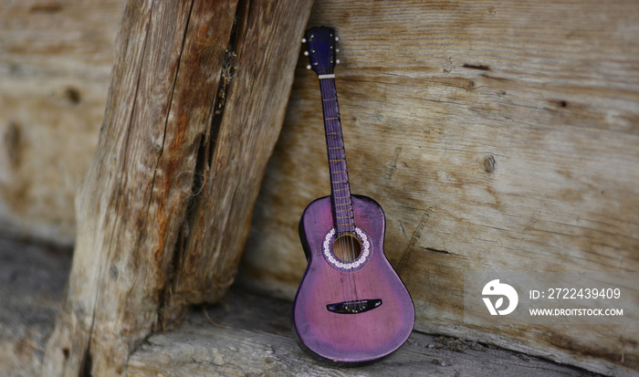 a guitar leaning against a stable on an old ranch