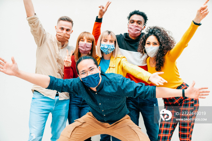 Multicultural people covered by protective face masks smiling at camera - New normal friendship concept with young friends having fun outdoor - Bright filter