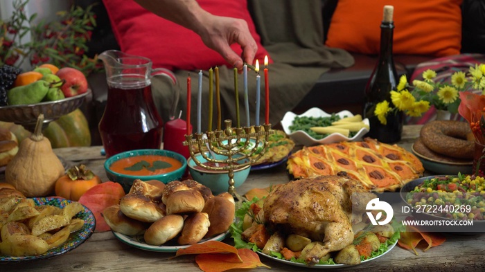 Lighting the Menorah lights. Menorah candles. Festive Hanukkah dinner at home with family. Traditional kosher Jewish food on the table - sufganiyot, latkes, cottage cheese and cheese meals