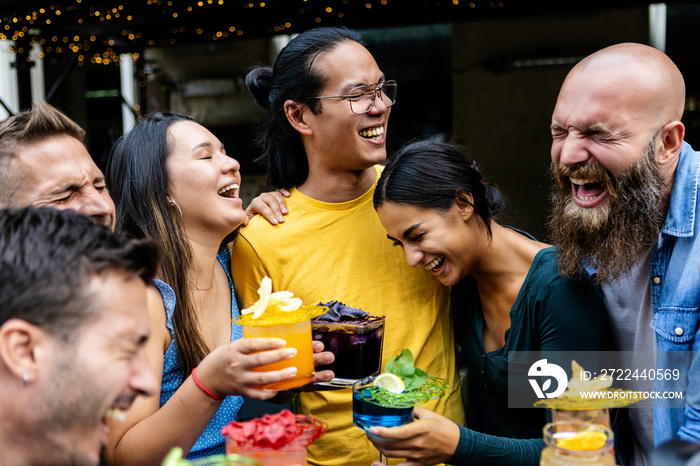 Group of happy young multiracial united friends having fun laughing together drinking cocktails at bar terrace in summer holidays - Youth, lifestyle and millennial people concept