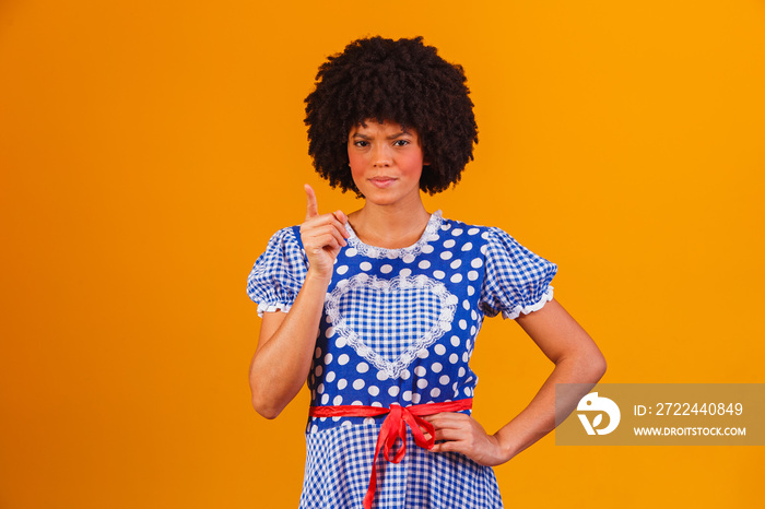 Brazilian afro woman wearing typical clothes for the Festa Junina in yellow background.