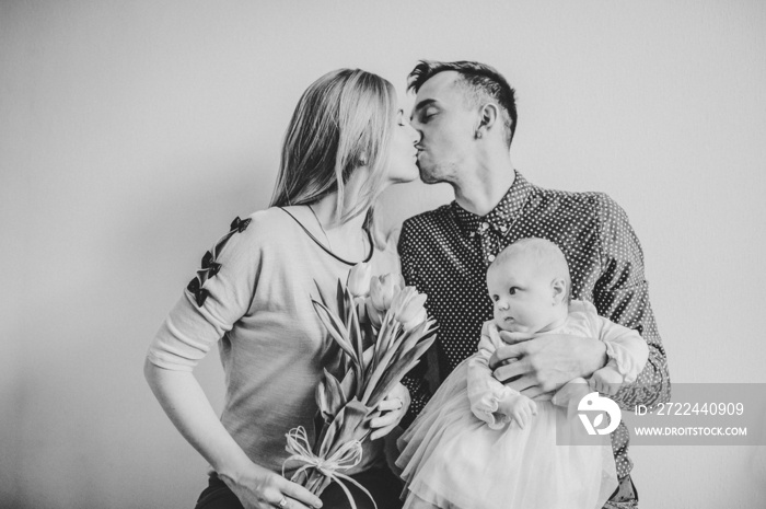 Happy fathers day! Daughter with mom congratulate dad and give her bouquet of flowers. Happy family portrait kissing and hugging, concept love. Mothers, fathers Day. black white photo.