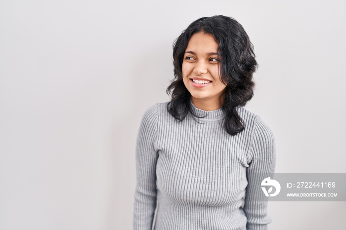 Hispanic woman with dark hair standing over isolated background smiling looking to the side and staring away thinking.