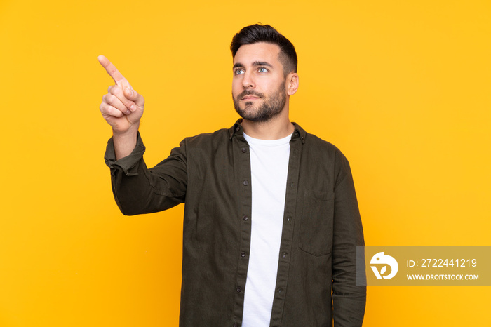 Man over isolated yellow background touching on transparent screen