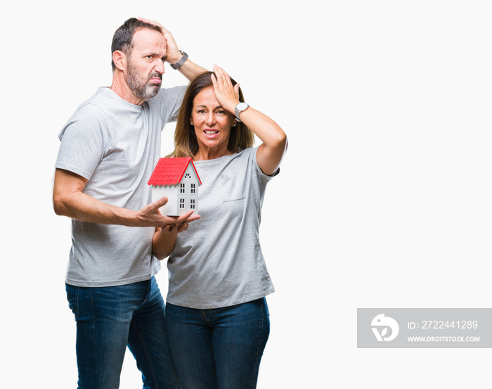 Middle age hispanic casual couple buying new house over isolated background stressed with hand on head, shocked with shame and surprise face, angry and frustrated. Fear and upset for mistake.