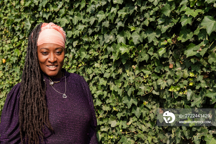 Portrait of beautiful woman with dreadlocks in front of ivy wall