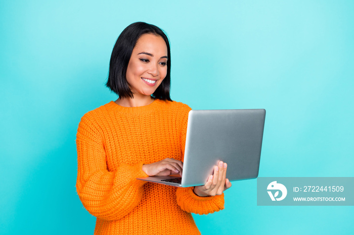 Photo of sweet charming lady wear orange sweater typing samsung apple modern device isolated turquoise color background