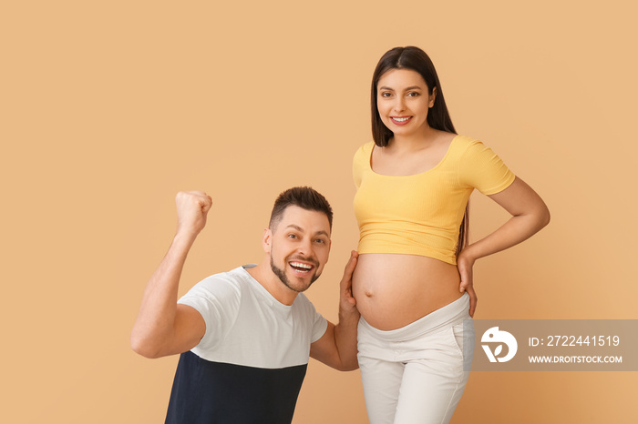 Beautiful pregnant couple on color background