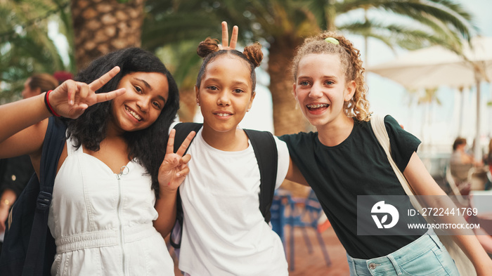 Three girls friends pre-teenage standing on the street smiling, hugging each other making faces for the camera. Three teenagers on the outdoors in urban cityscape background