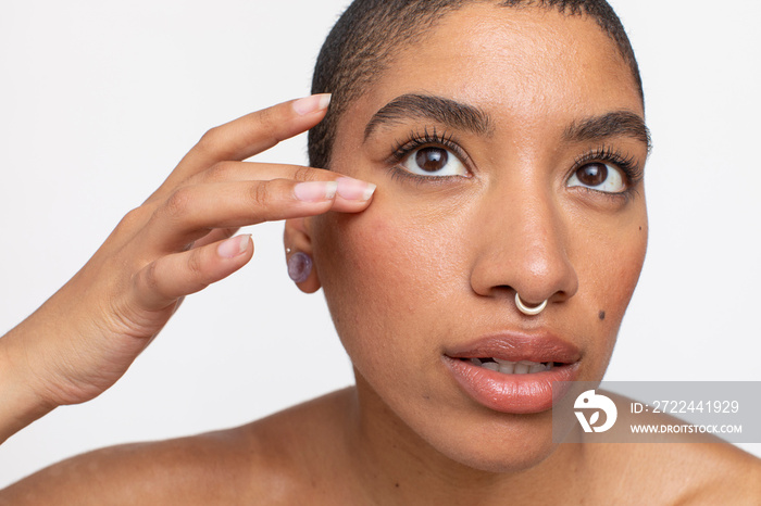 Studio portrait of woman with nose ring touching face