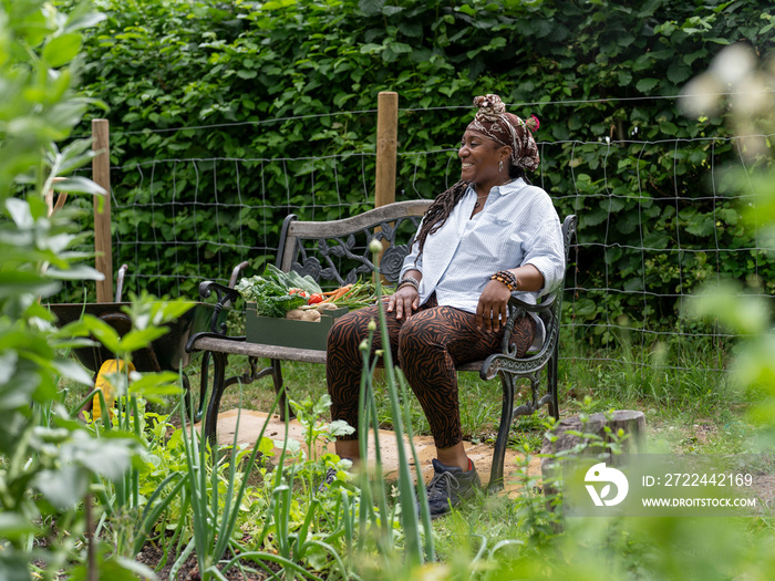 Smiling woman resting on bench after working in garden