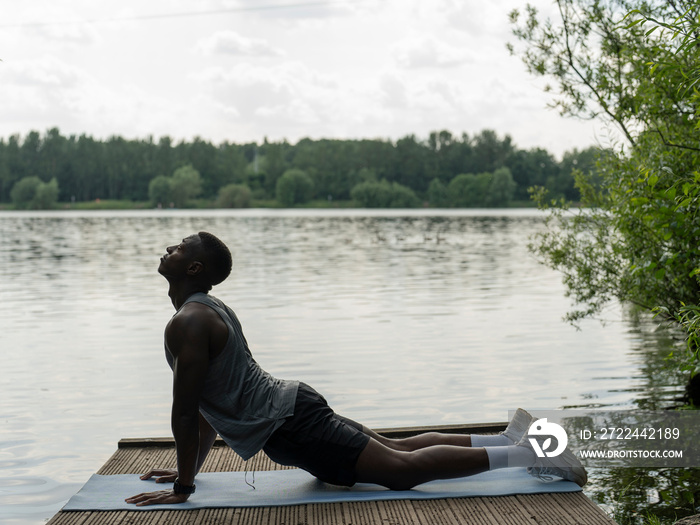 Man practicing yoga by lake