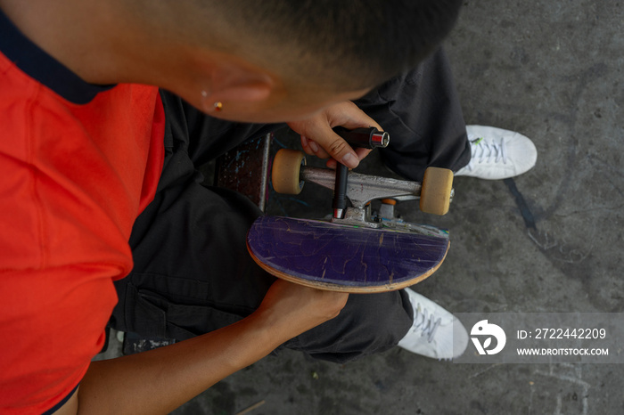 Close-up of young man fixing skateboard