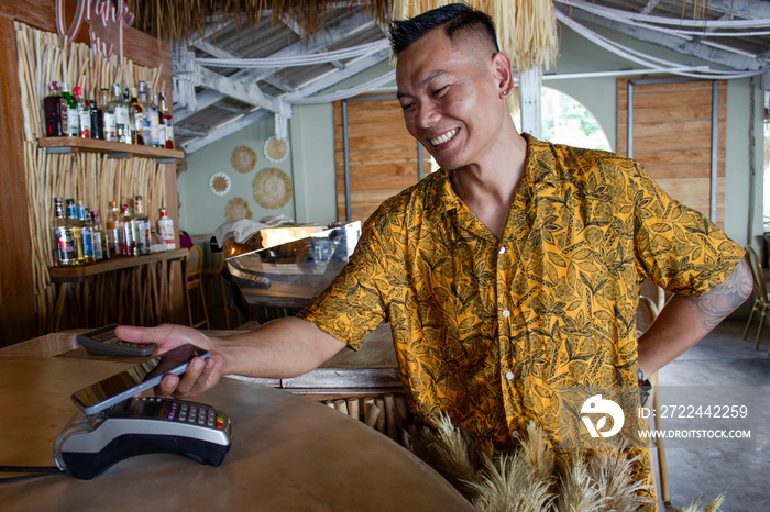 Man paying with smart phone in beach bar