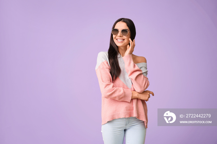 Young woman with stylish sunglasses on color background