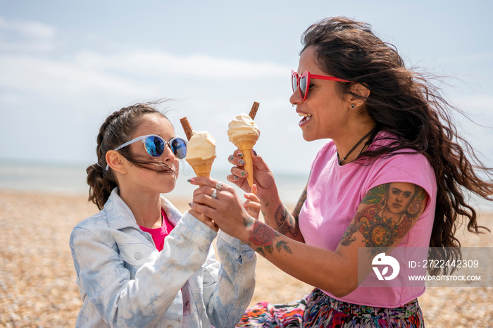 Mother and daughter (8-9) eating ice cream on beach