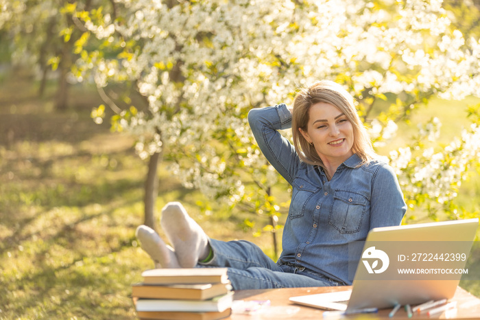 Attractive young woman with toothy smile using laptop outdoors.