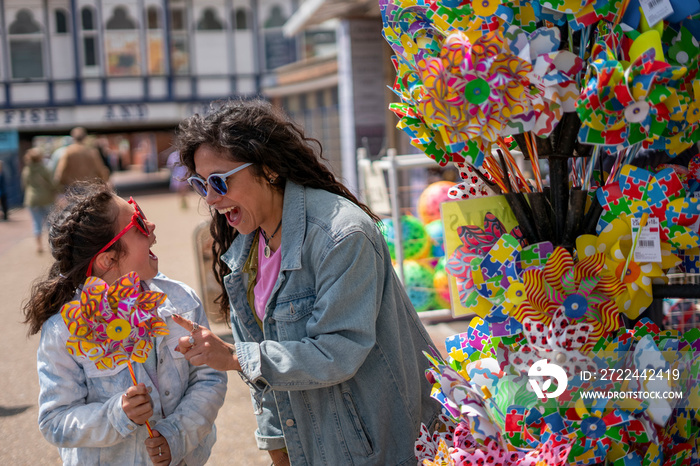 Smiling mother and daughter (8-9) buying pinwheel at street stand