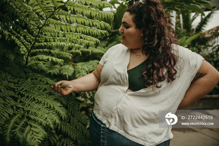 plus size woman looks at ferns