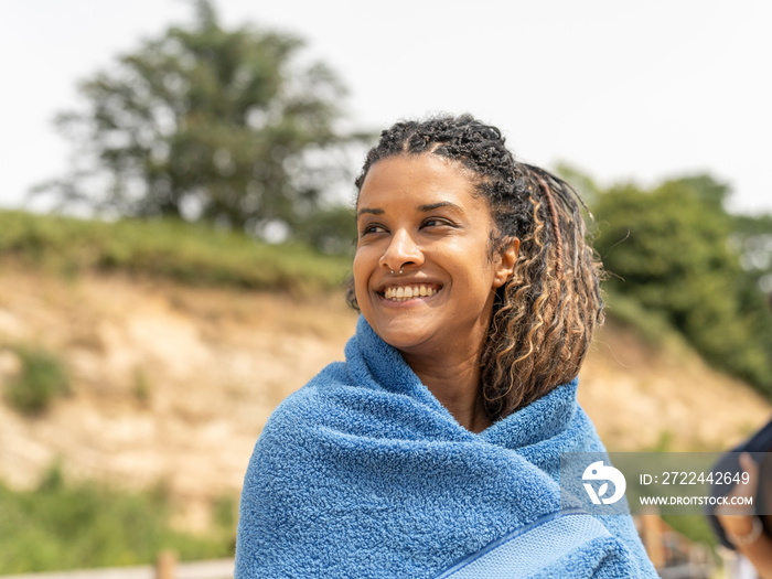 Portrait of smiling woman wrapped in towel on beach