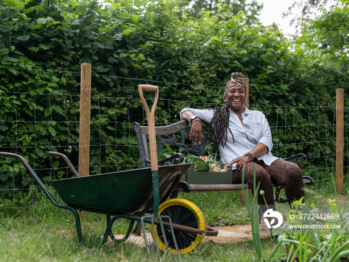 Smiling woman resting on bench after working in garden