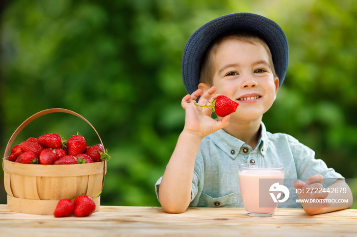 little boy eats ripe strawberry and drinks yogurt from glass