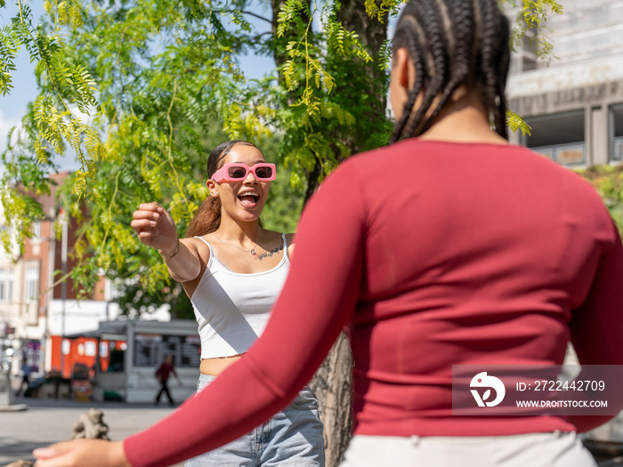 Two female friends greeting in city street