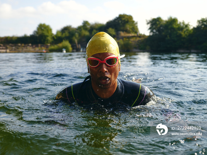 Woman in swimming cap and goggles swimming in river