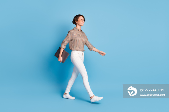 Full body profile photo of satisfied lady walking hand hold laptop toothy smile isolated on blue color background