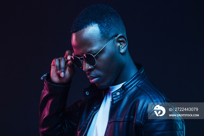 Close-up studio shot of african american male model wearing trendy sunglasses and leather jacket