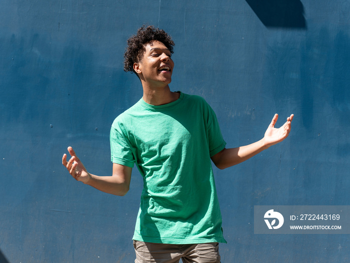 Portrait of young man enjoying sunny day against blue wall