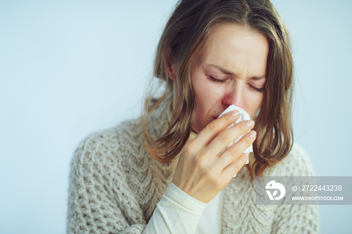 woman with napkin coughing on winter light blue background