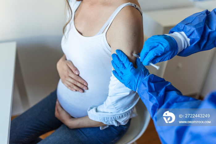 Pregnant Vaccination. Doctor giving COVID -19 coronavirus vaccine injection to pregnant woman. Doctor Wearing Blue Gloves Vaccinating Young Pregnant Woman In Clinic. People vaccination concept.