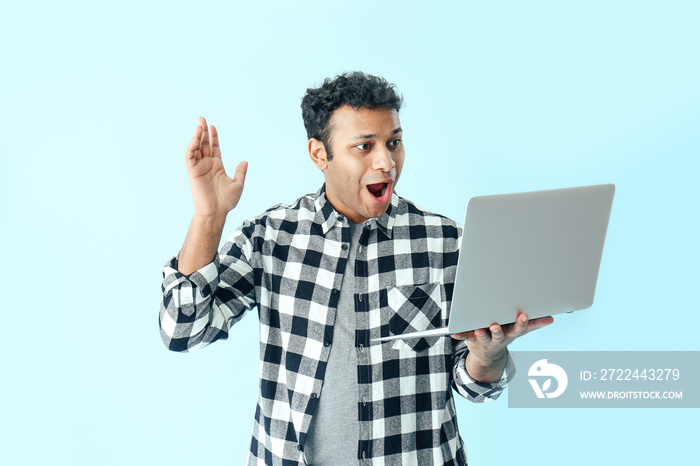 Happy man with laptop on color background