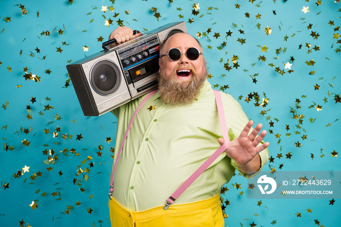 Close-up portrait of his he nice attractive cool carefree cheerful cheery funky bearded guy carrying boombox having fun confetti flying isolated over bright vivid shine vibrant blue color background