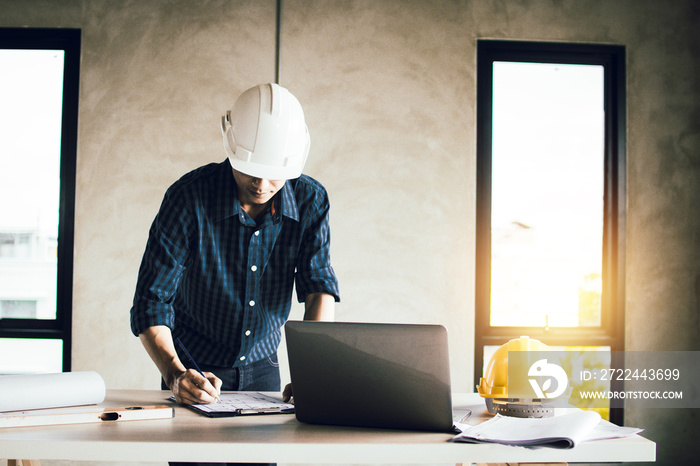 engineer working on blue print and search on laptop in construction site