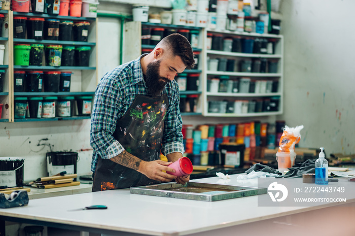 Male worker mixing colors for screen printing in a workshop