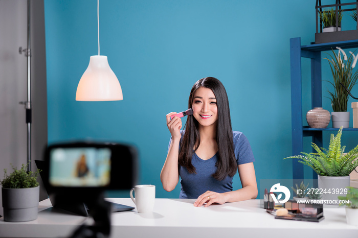 Creative influencer filming make up tutorial showing cosmetic brush recording review using podcast equipment. Behind the scene of attractive vlogger creator advertising cosmetology product