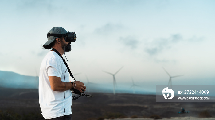 Drone engineer using first person view technology on the turbine farm - Alternative energy and aerial engineering concept