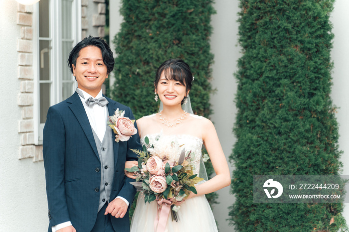 結婚式で結婚式場の庭でブーケを持つ新郎新婦（ガーデンウェディング）