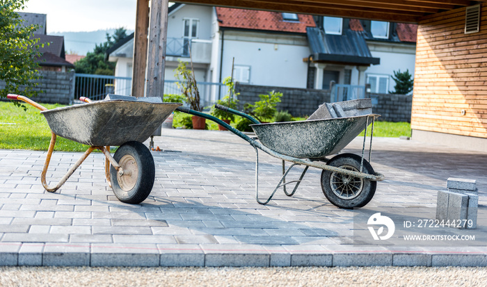 Laying gray concrete paving slabs in house courtyard driveway patio.