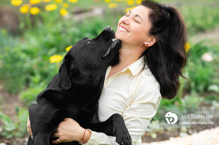 Woman playing with her black Labrador dog