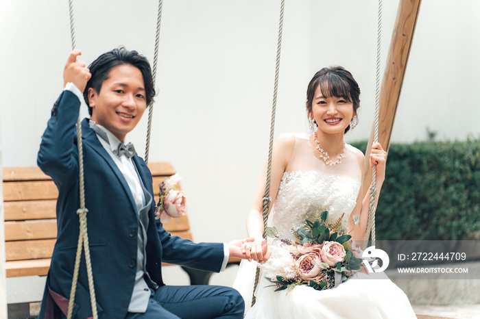 結婚式で結婚式場の庭でブランコに乗る新郎新婦（ガーデンウェディング）