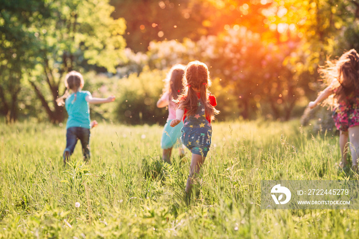 Large group of kids, friends boys and girls running in the park on sunny summer day in casual clothes .