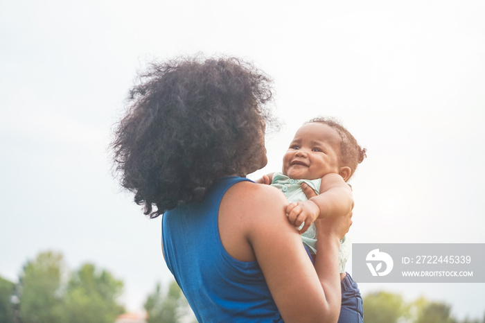 Happy african mother playing with her daughter outdoor - Afro mum and child having fun together - Family, happiness and love concept - Soft focus on kid face