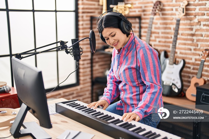 Young chinese woman musician playing piano keyboard at music studio