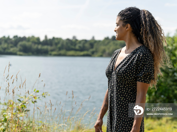 Portrait of woman looking at lake on sunny day