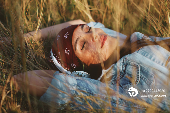 Closeup of young woman listens to music and lying in the meadow